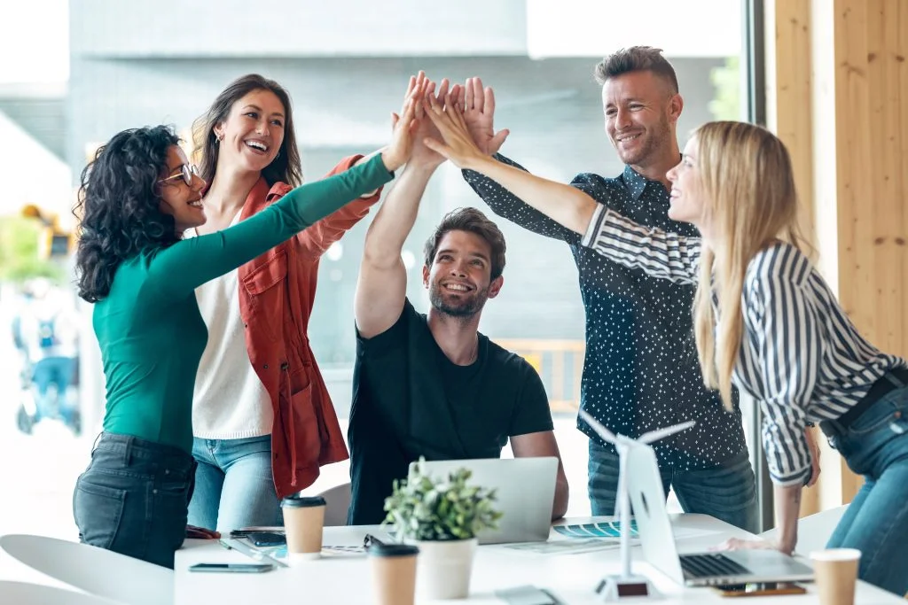 Group of successful smart business team celebrating good job whi Shot of group of successful smart business team celebrating good job while holding up their right hands on coworking place.