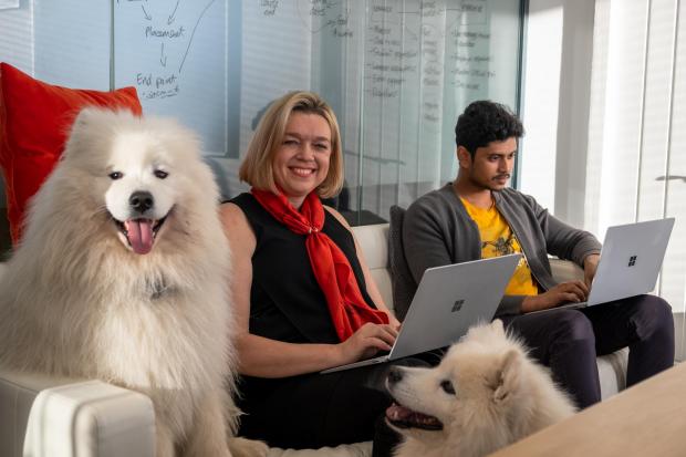 Happy colleagues with a big fluffy white dog - dog-friendly workplace