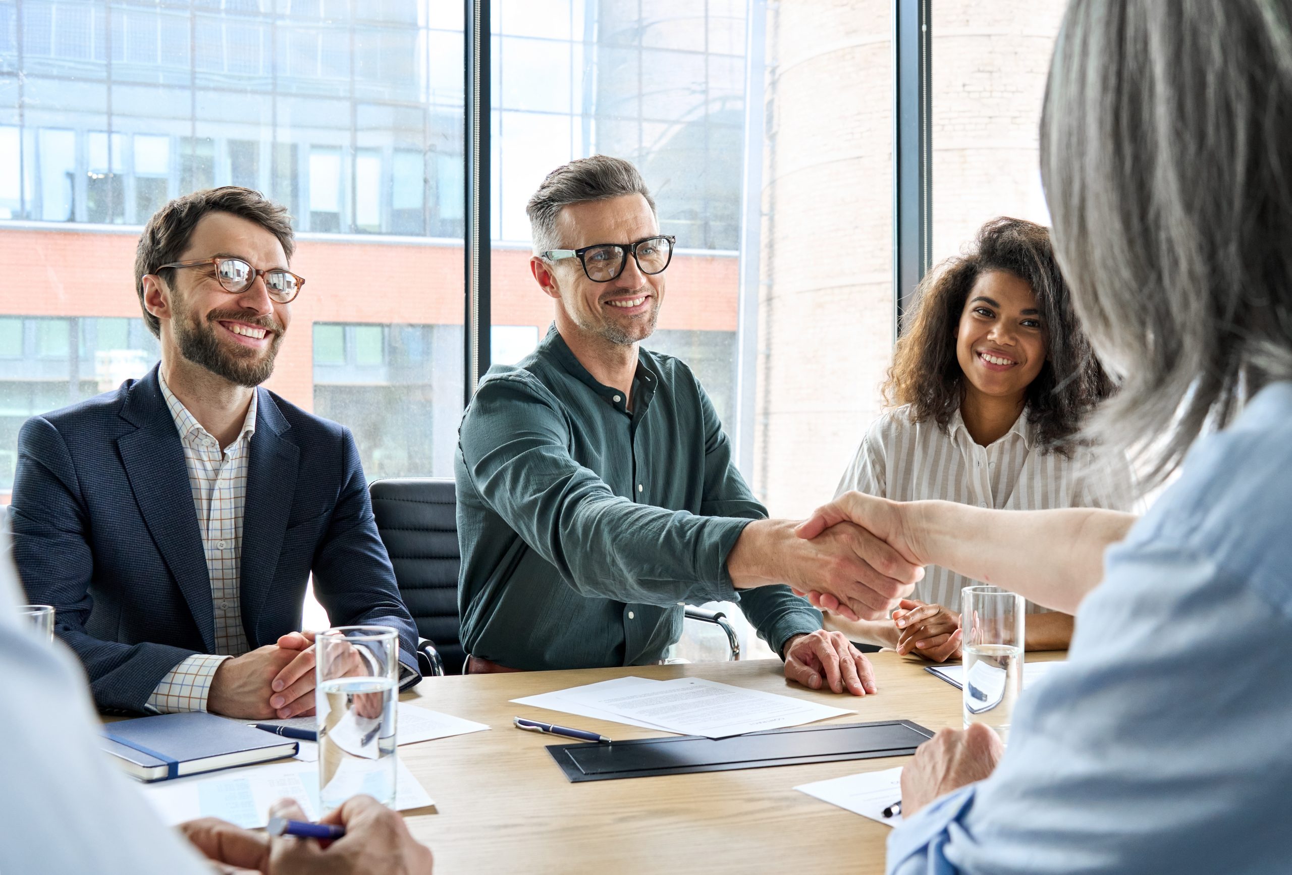 Happy businessman and businesswoman shaking hands at group meeting. Happy businessman and businesswoman shaking hands at group board meeting. Professional business executive leaders making handshake agreement successful company trade partnership handshake concept.