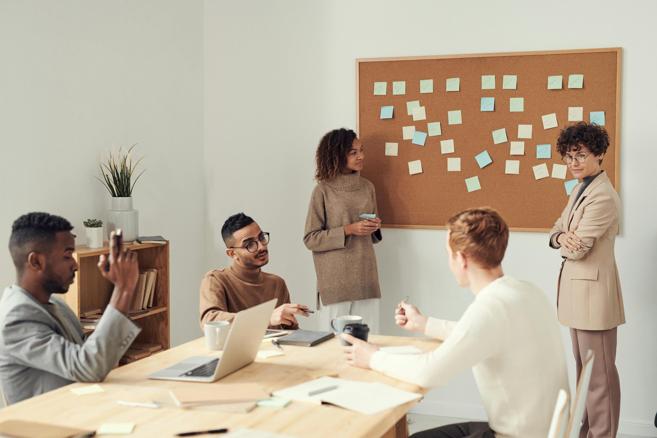 people in an office in front of a pin board.