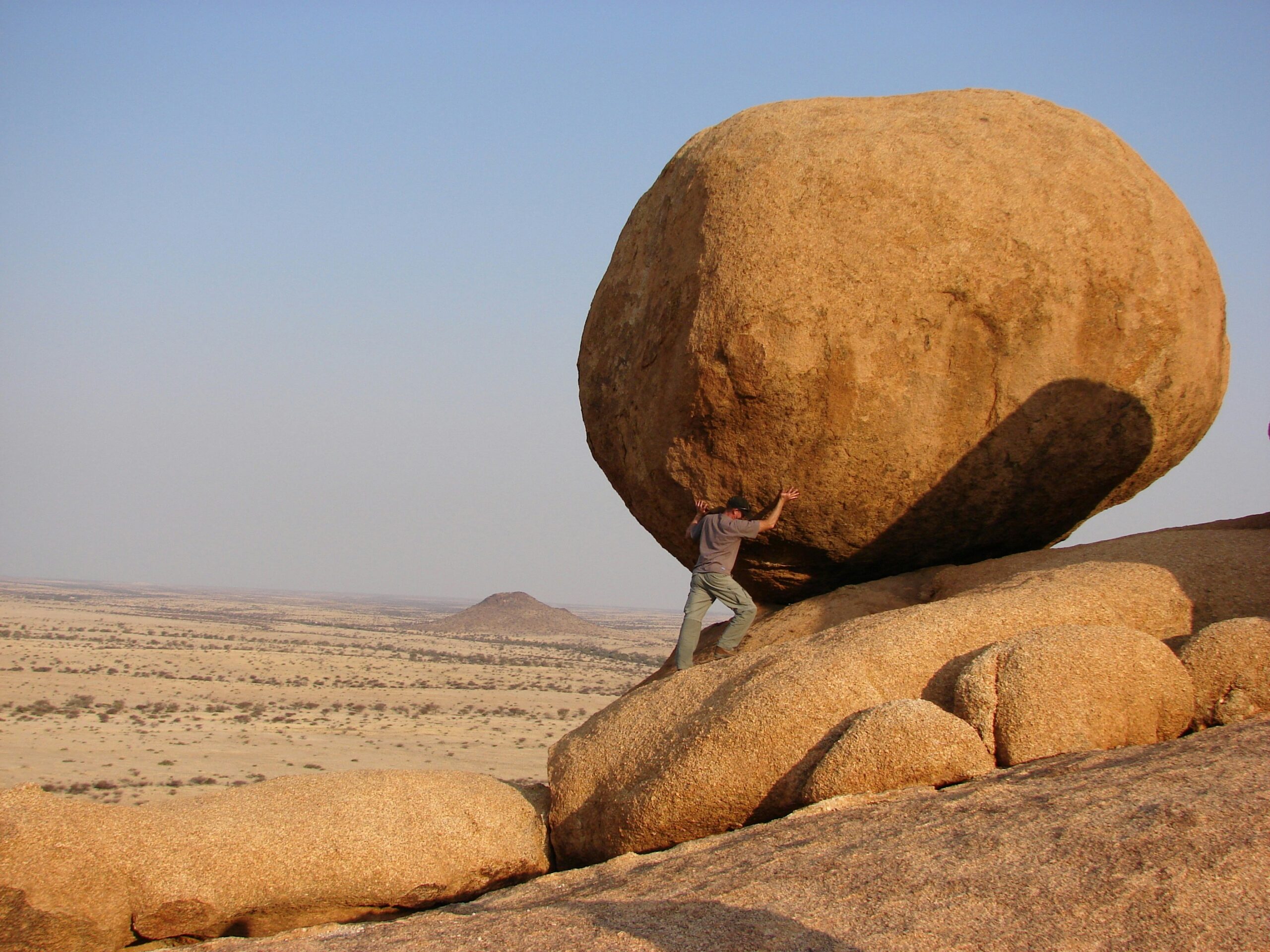 man holding up a boulder