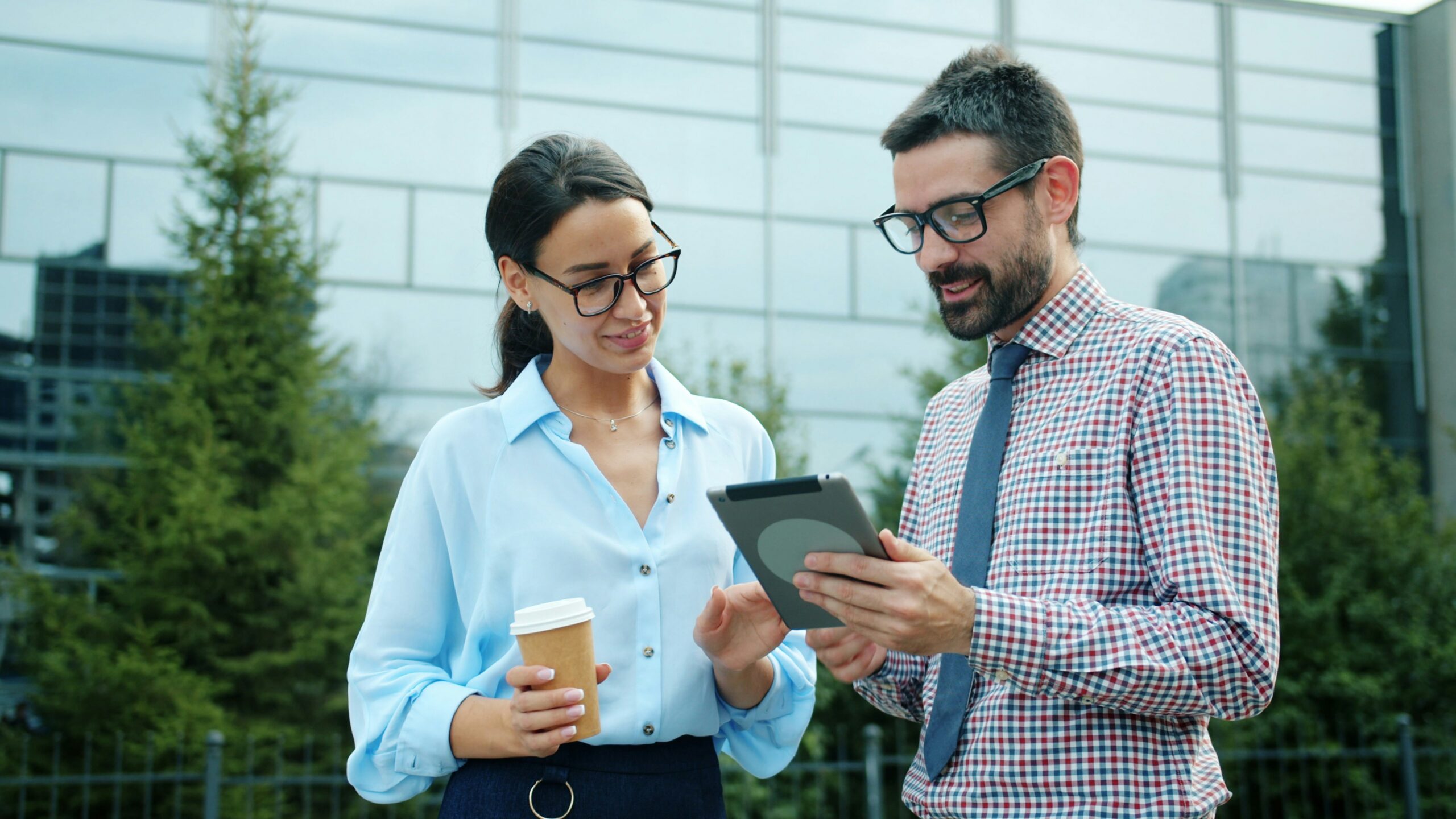 two people outside looking over a work tablet