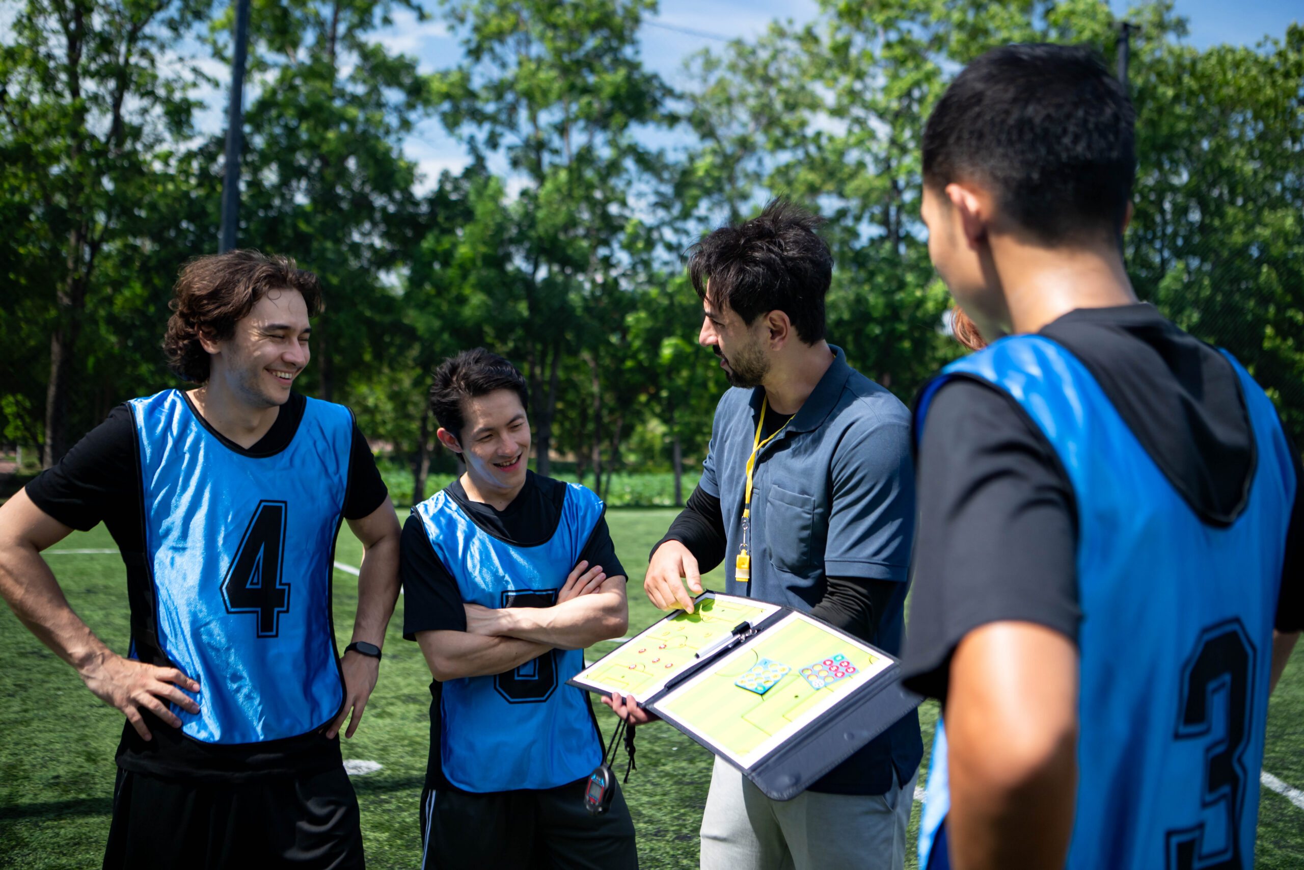 Soccer coach explaining tactics and game strategy to players during a team briefing Soccer coach explaining tactics and game strategy to players during a team briefing on an outdoor football field before a match