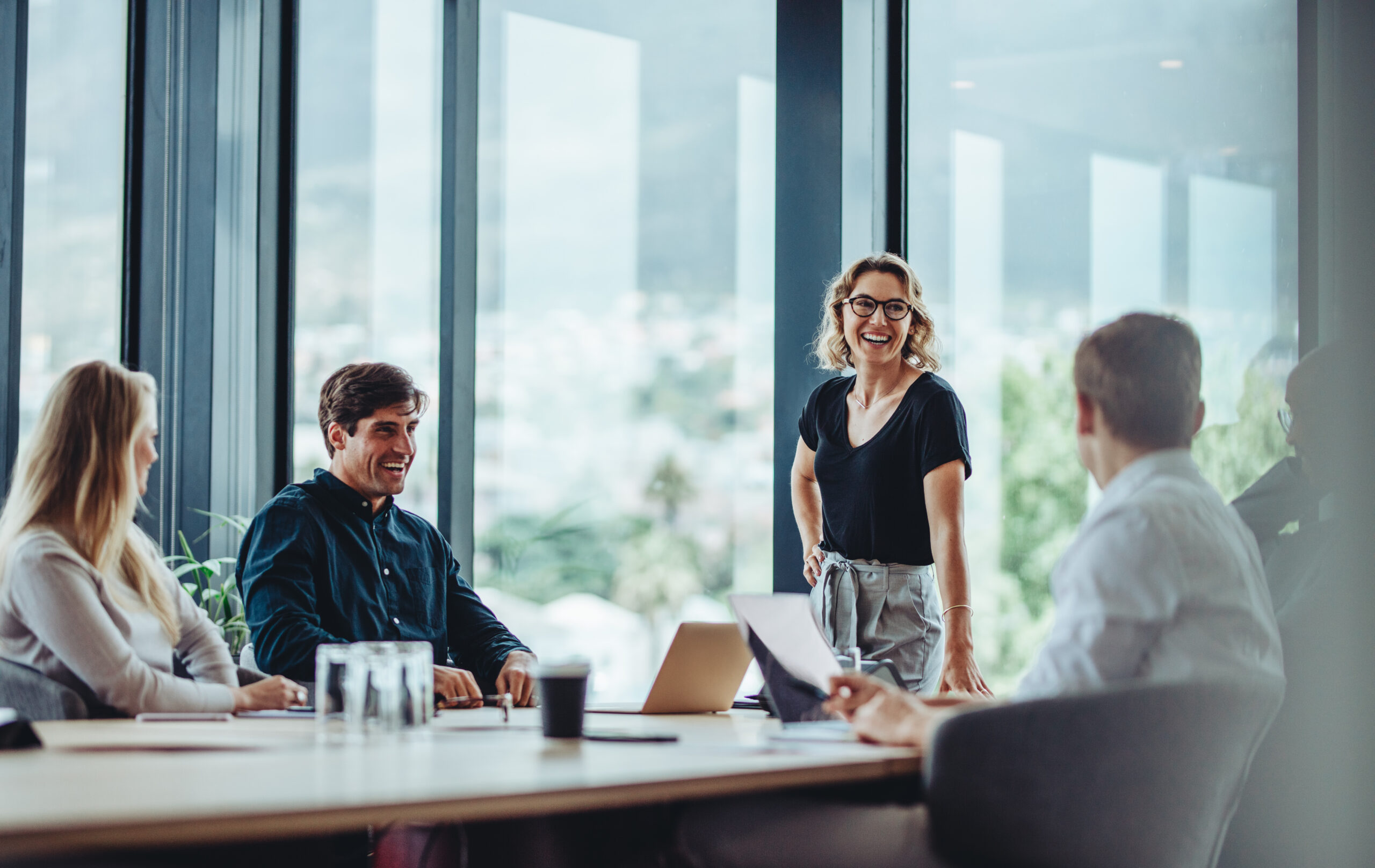 Business people having casual discussion during meeting Office colleagues having casual discussion during meeting in conference room. Group of men and women sitting in conference room and smiling.