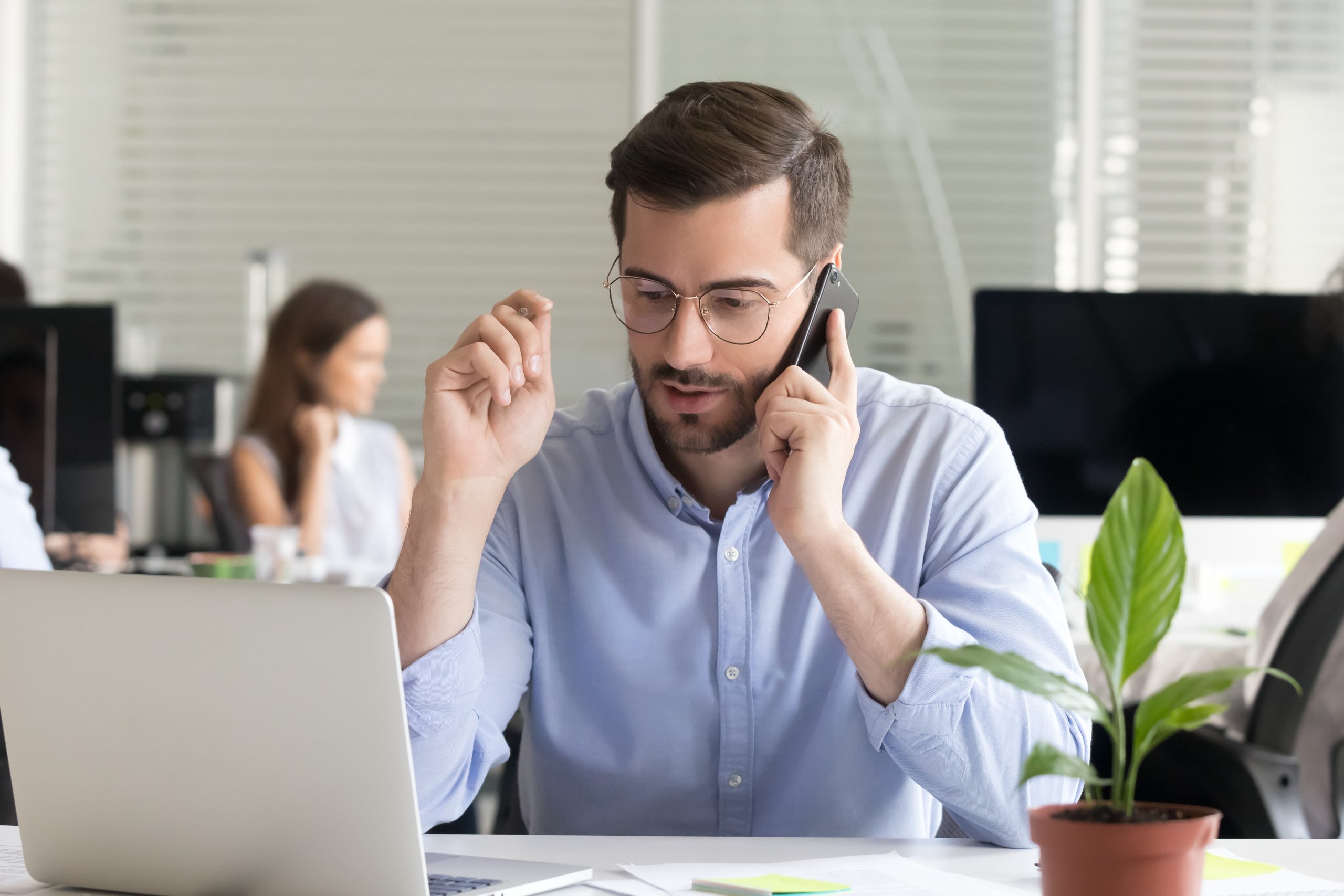 Marketing sales manager consulting client making offer selling talking on phone near laptop in office, serious business man making call negotiating speaking by mobile holding interview on cellphone