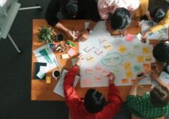 Group of business people writing sticky note and making mind map to brainstorming marketing idea at meeting. Top aerial view of investors sharing plan or strategy and stick note at paper. Convocation.