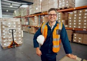 Factory employee looking at camera at industrial storehouse