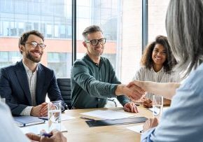 Happy businessman and businesswoman shaking hands at group board meeting. Professional business executive leaders making handshake agreement successful company trade partnership handshake concept.